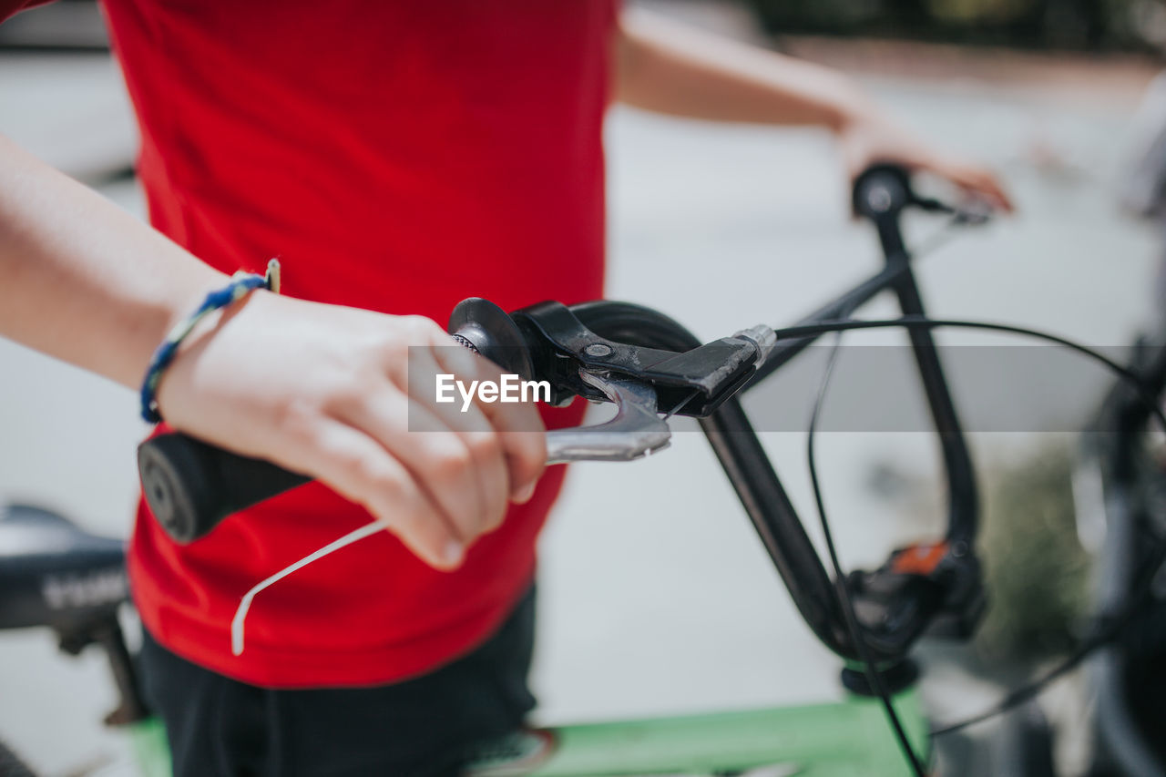 Midsection of boy holding bicycle handlebar