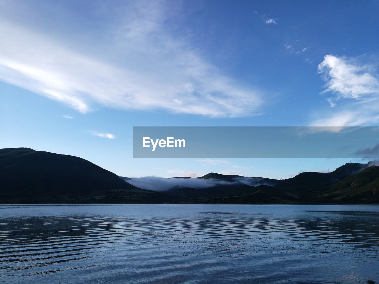 Scenic view of lake by mountains against sky