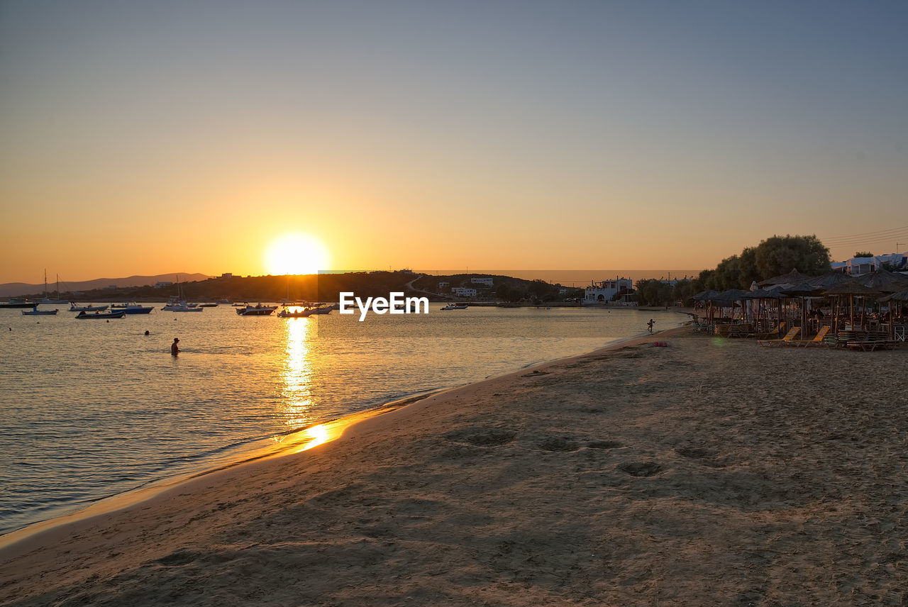 Scenic view of beach against clear sky during sunset