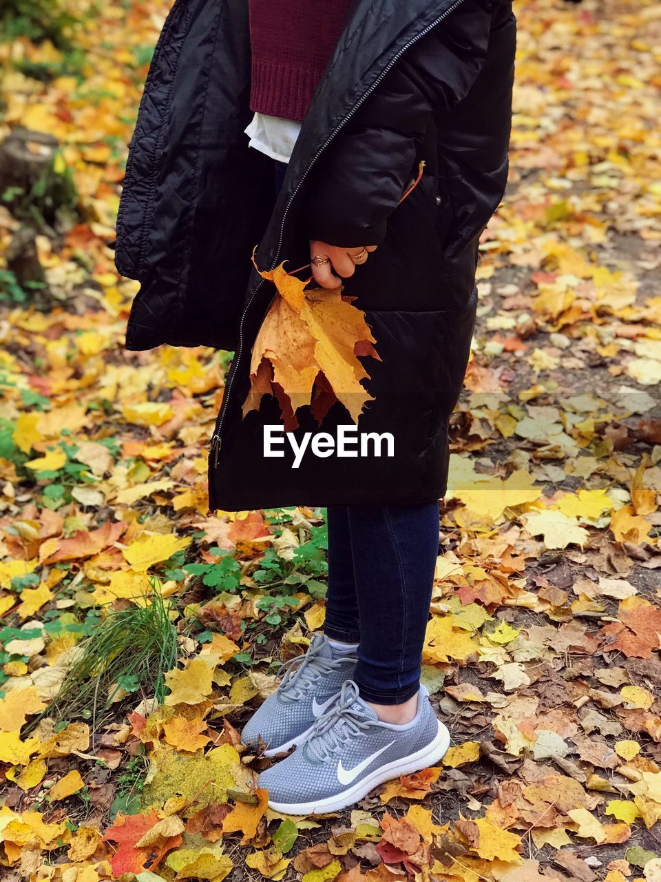 LOW SECTION OF PERSON STANDING ON DRY AUTUMN LEAVES