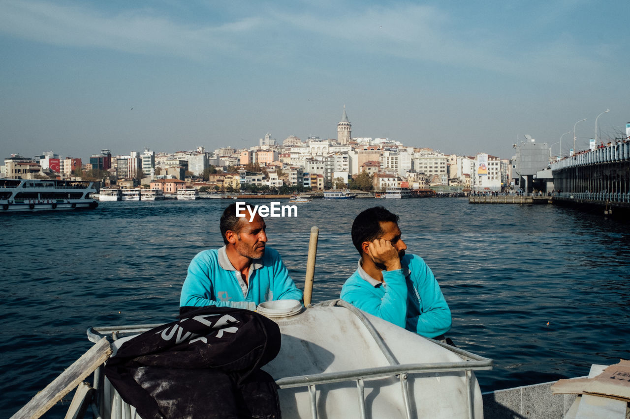 PEOPLE SITTING ON RIVER IN CITY