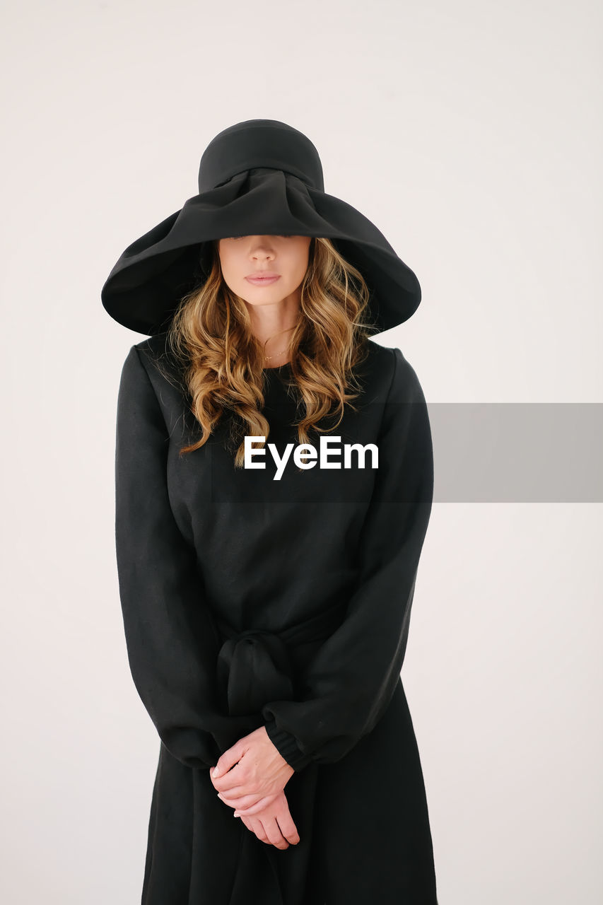 Young woman wearing hat standing against white background