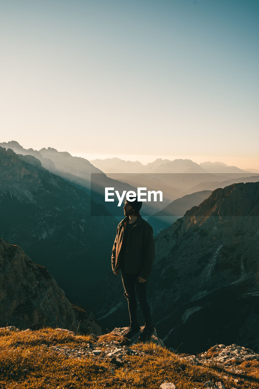 MAN LOOKING AT MOUNTAIN AGAINST SKY