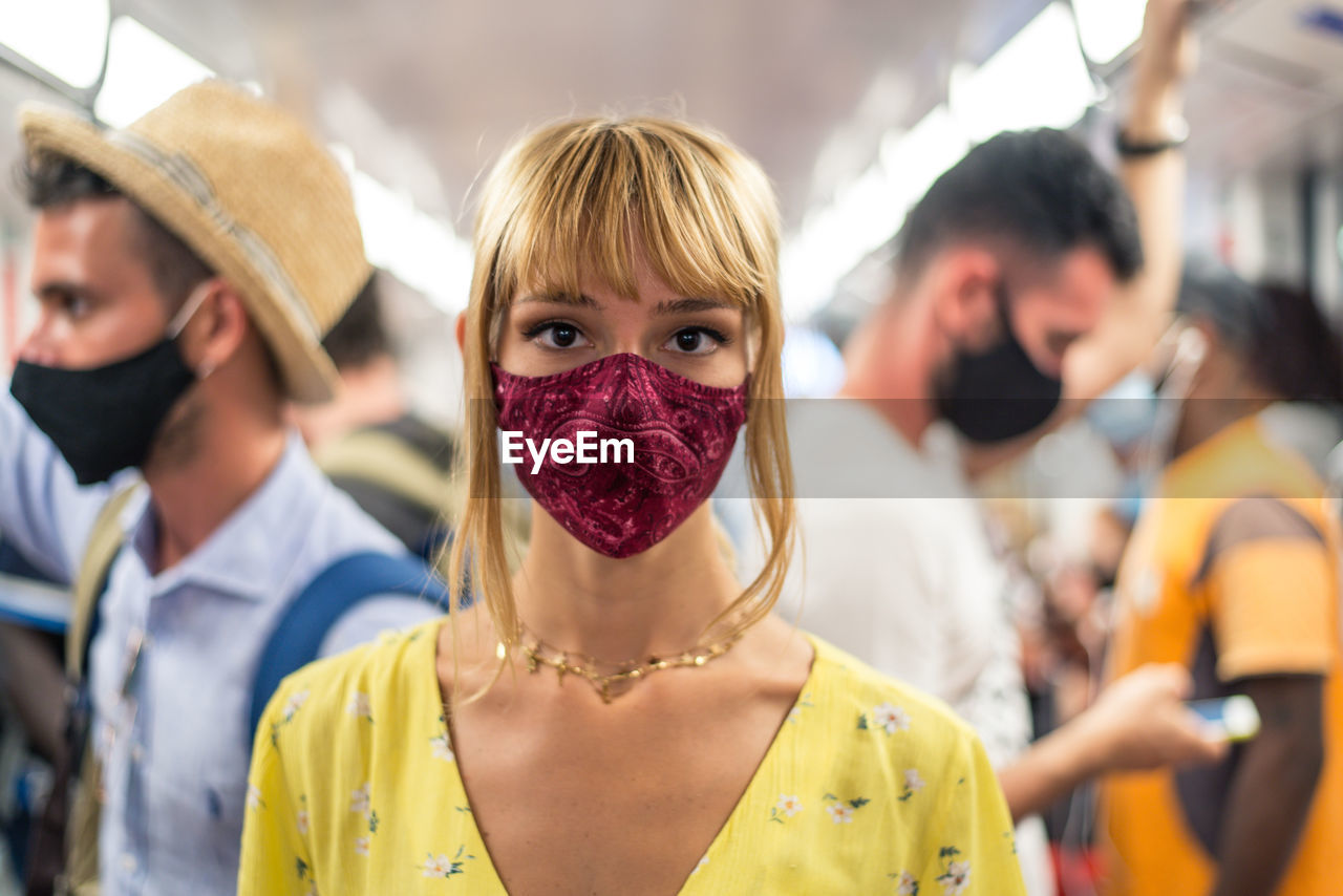 Portrait of woman wearing mask standing in bus