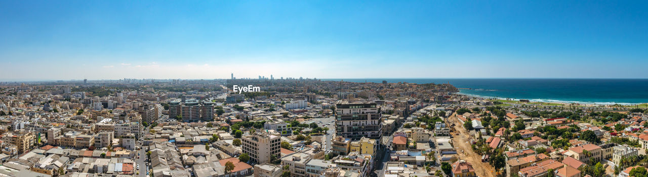 Aerial view of city by sea against clear sky