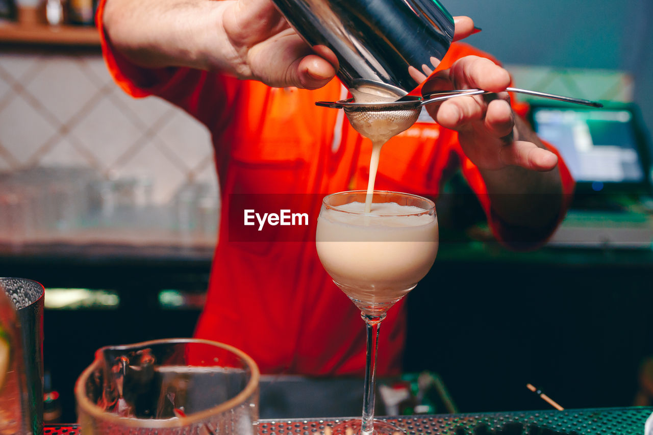 Midsection of bartender preparing drink