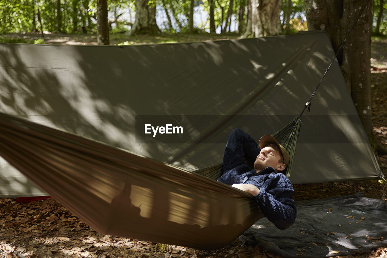 Man sleeping on hammock in forest