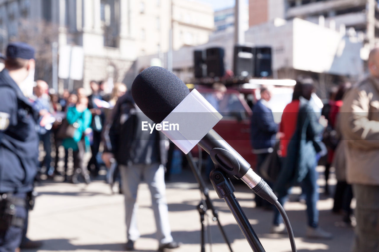 Close-up of microphone with people in background on street