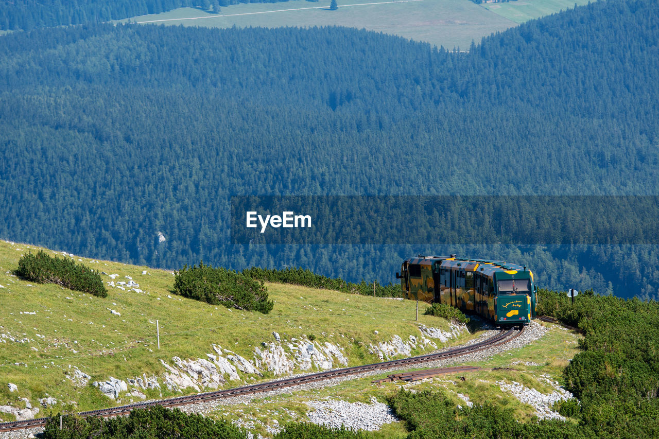 HIGH ANGLE VIEW OF TRAIN ON FIELD BY MOUNTAIN