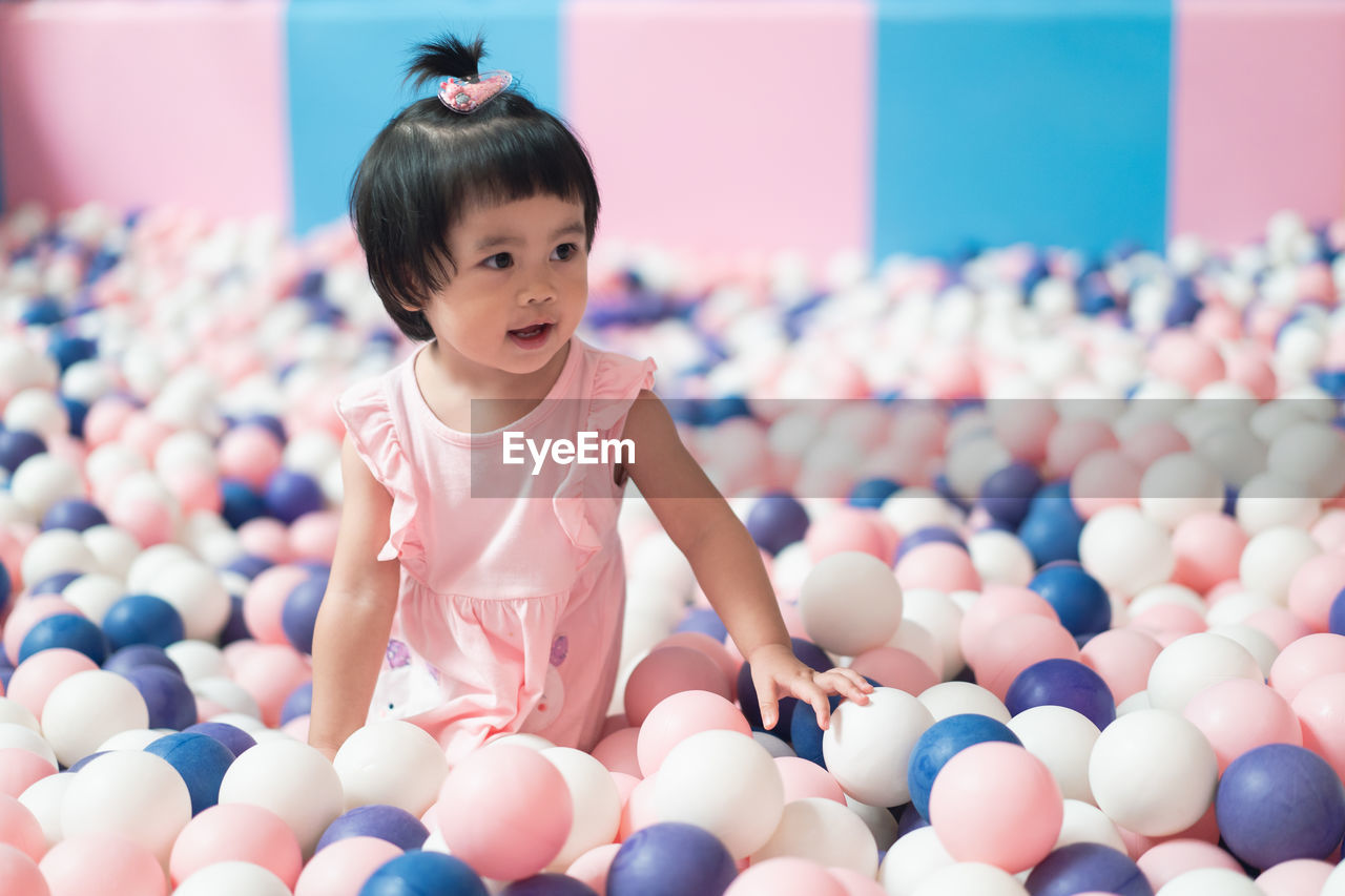 Cute baby girl standing in ball pool