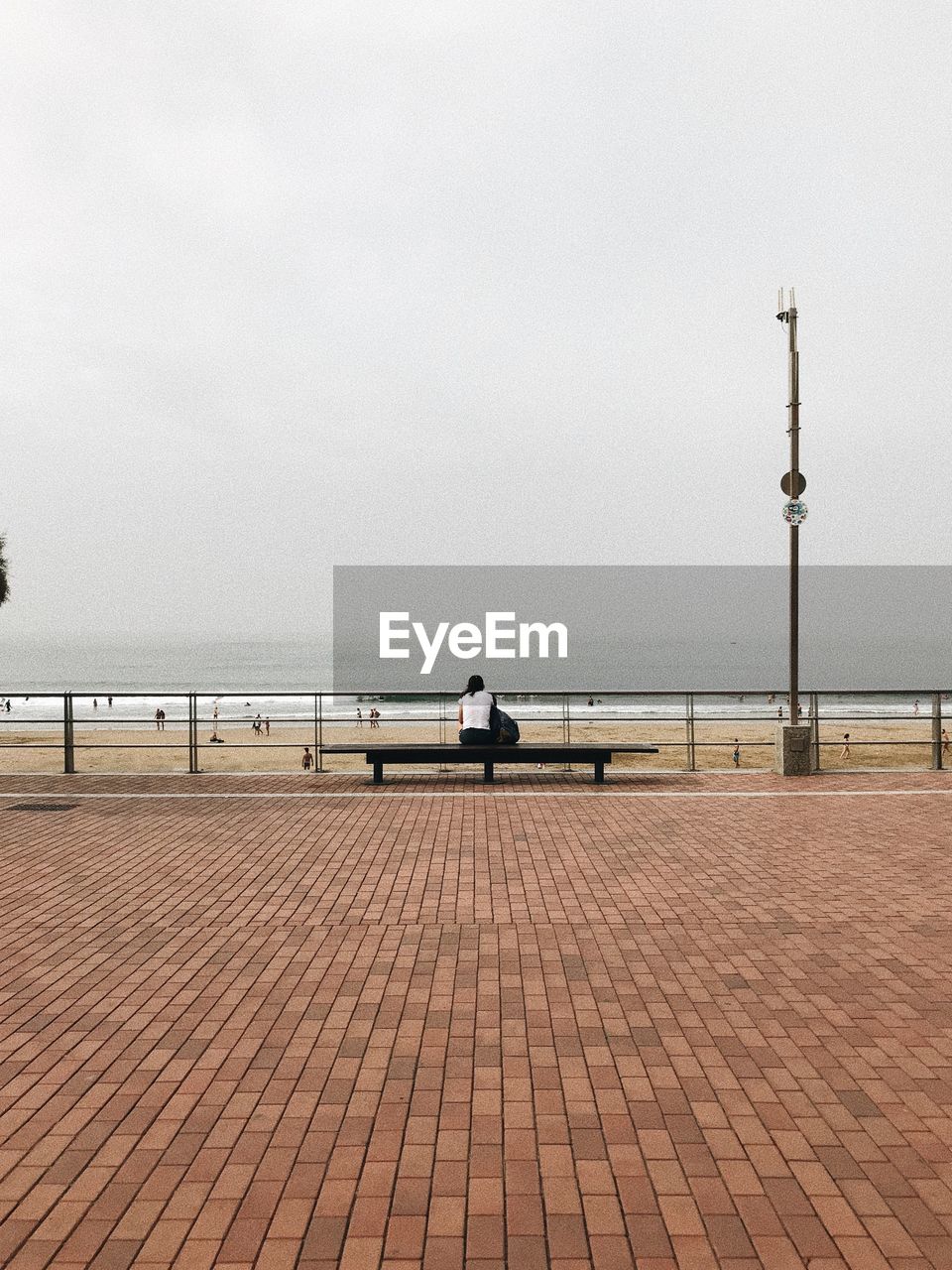 REAR VIEW OF PEOPLE OVERLOOKING SEA AGAINST SKY