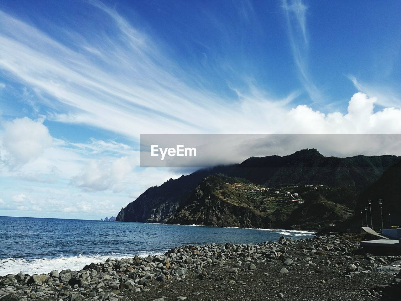 View of calm blue sea against mountain range