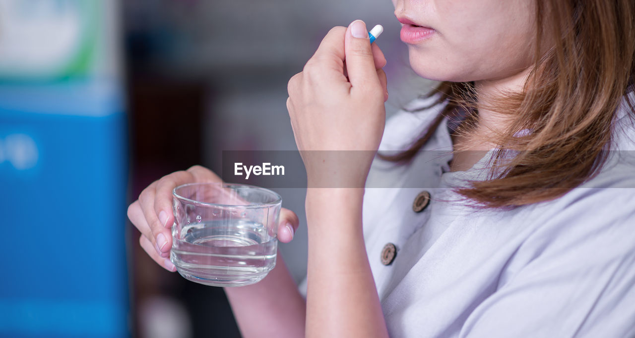 MIDSECTION OF WOMAN DRINKING WATER