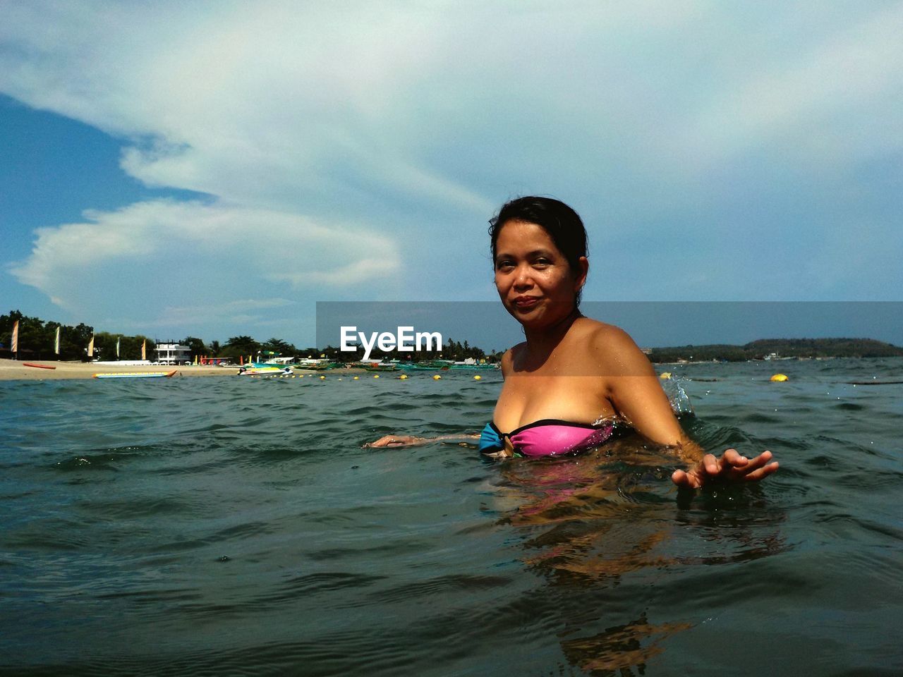 Portrait of smiling woman swimming in sea against sky