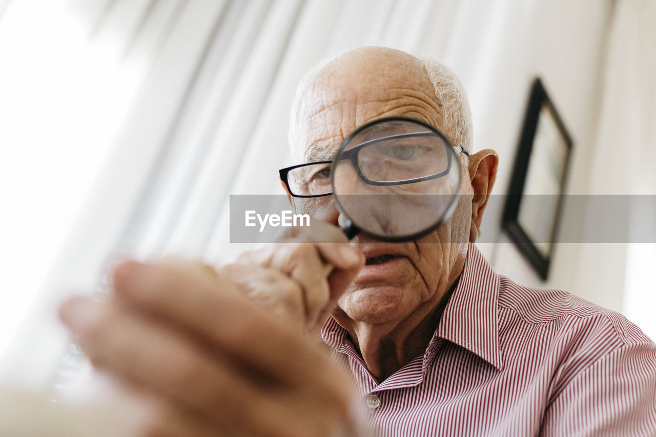 Retired senior male looking through magnifying glass at fossil
