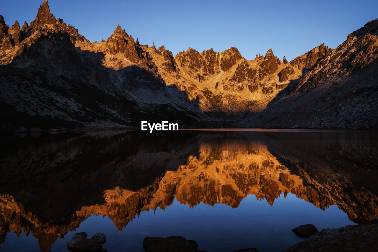 REFLECTION OF MOUNTAIN RANGE IN LAKE AGAINST SKY