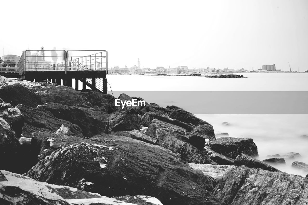 water, black and white, sea, sky, monochrome photography, nature, coast, rock, monochrome, beach, architecture, built structure, day, scenics - nature, land, shore, tranquility, no people, beauty in nature, tranquil scene, outdoors, travel destinations, clear sky, travel, pier, ocean, transportation, environment, tourism