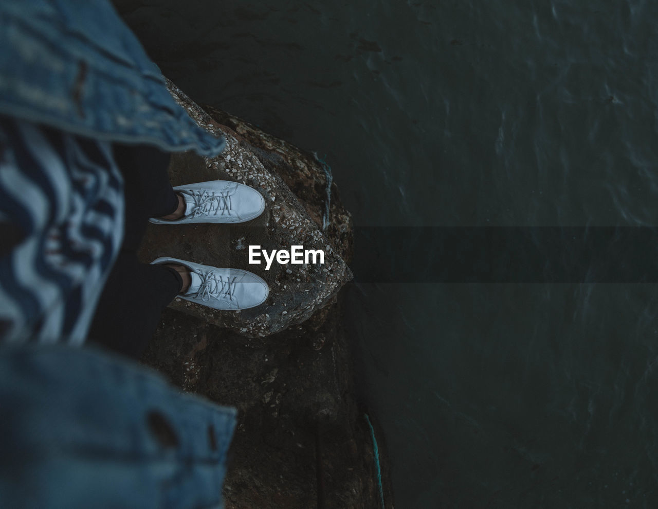 Low section of person standing over sea on rock