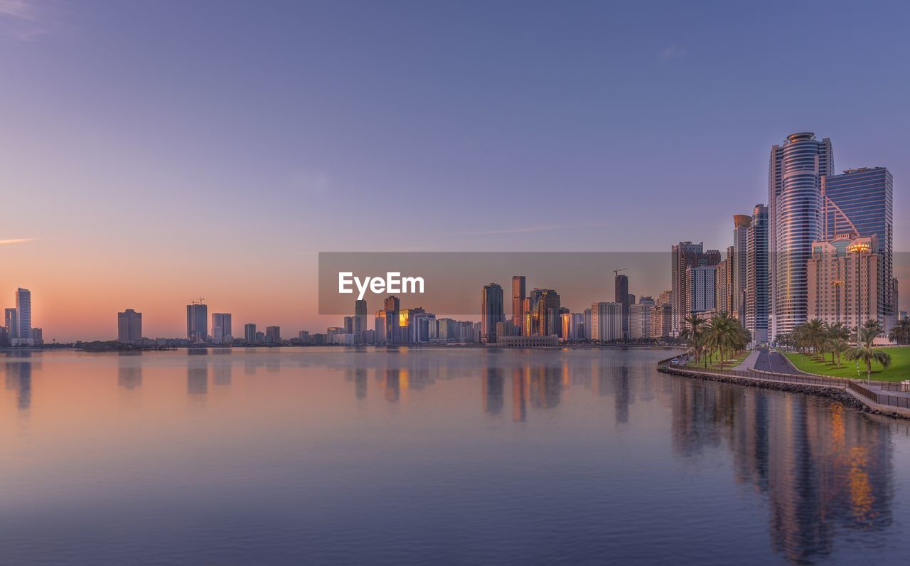 Emirate of sharjah by lake against sky during sunset