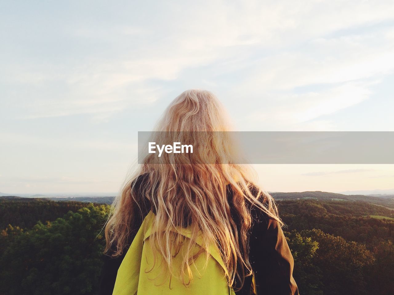 Rear view of woman standing against sky during sunset