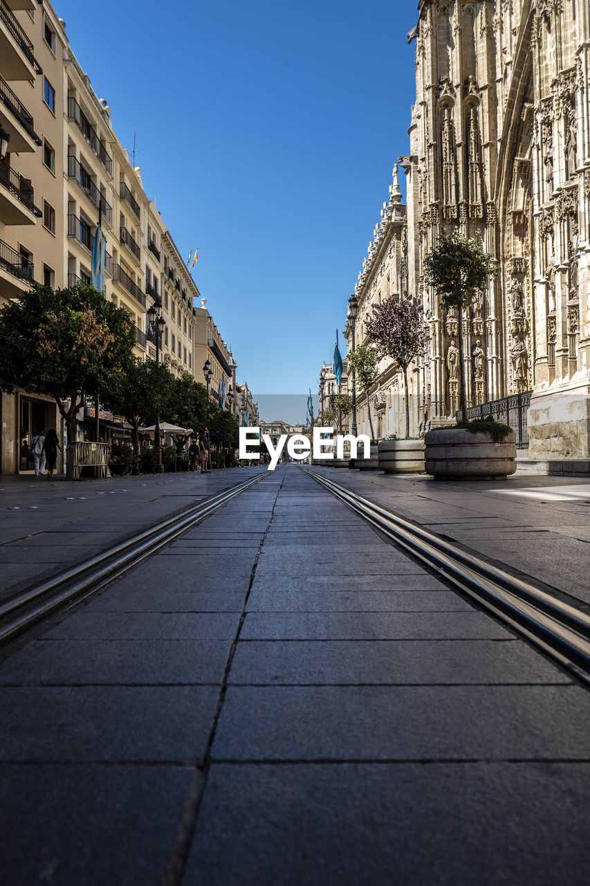 Surface level of road amidst buildings against clear sky