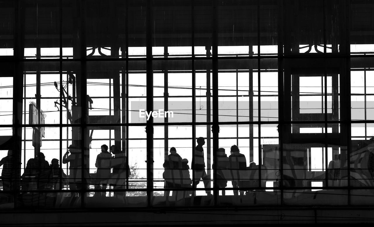 SILHOUETTE PEOPLE SITTING IN GLASS BUILDING