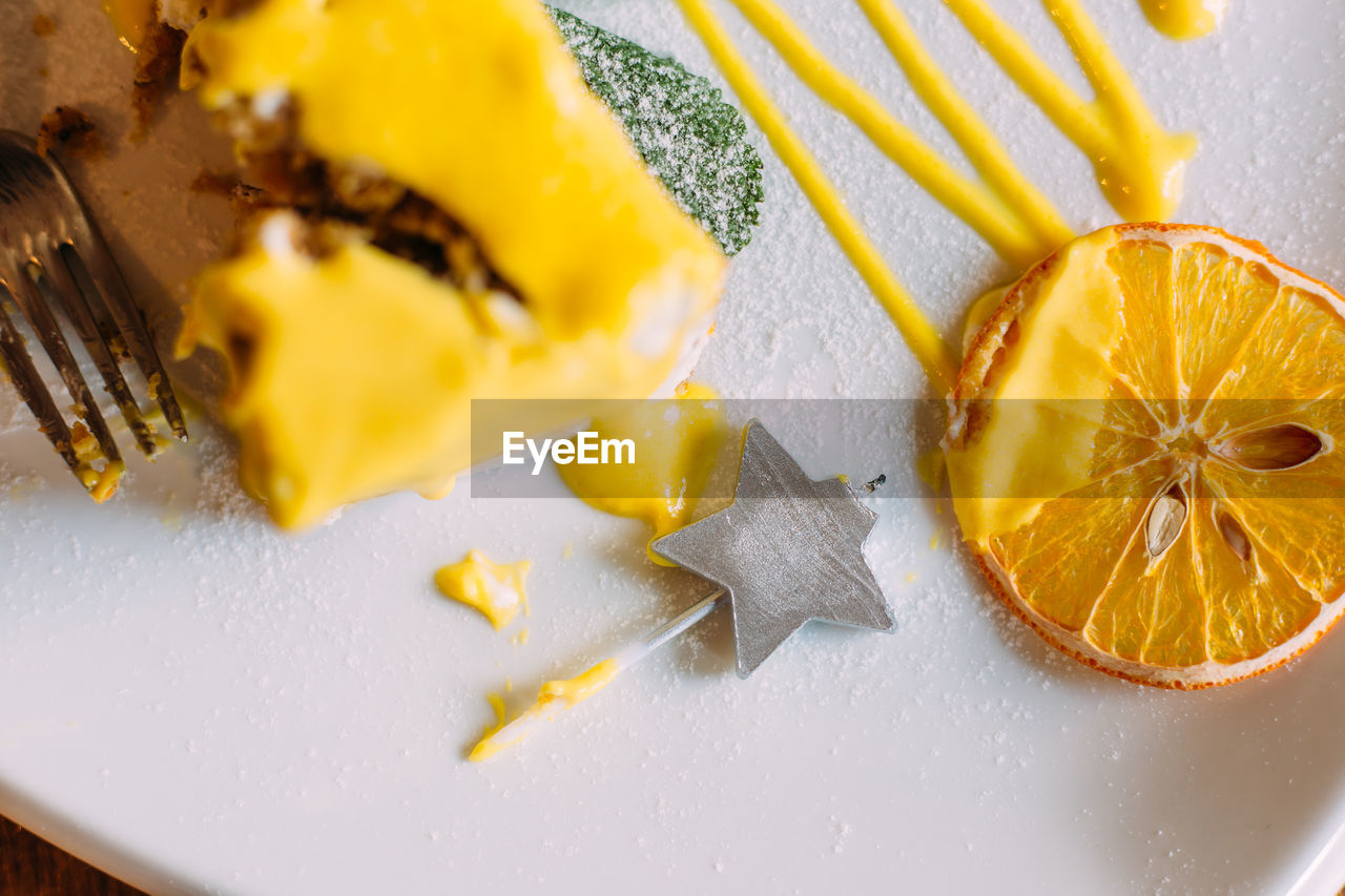 Piece of carrot cake with yellow glaze, dried orange and garnished with mint