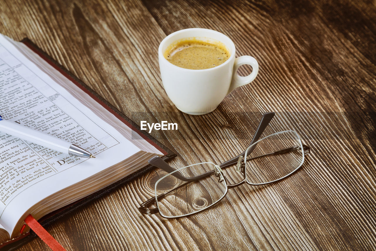 HIGH ANGLE VIEW OF COFFEE CUP ON BOOK