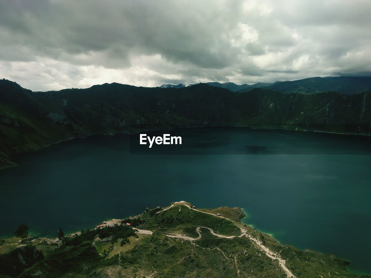 Scenic view of lake and mountains against cloudy sky