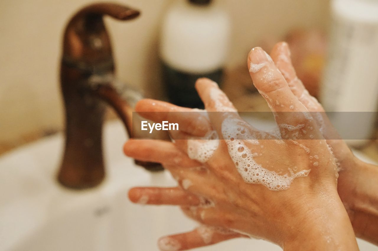 Close-up of woman washing hands in sink at bathroom