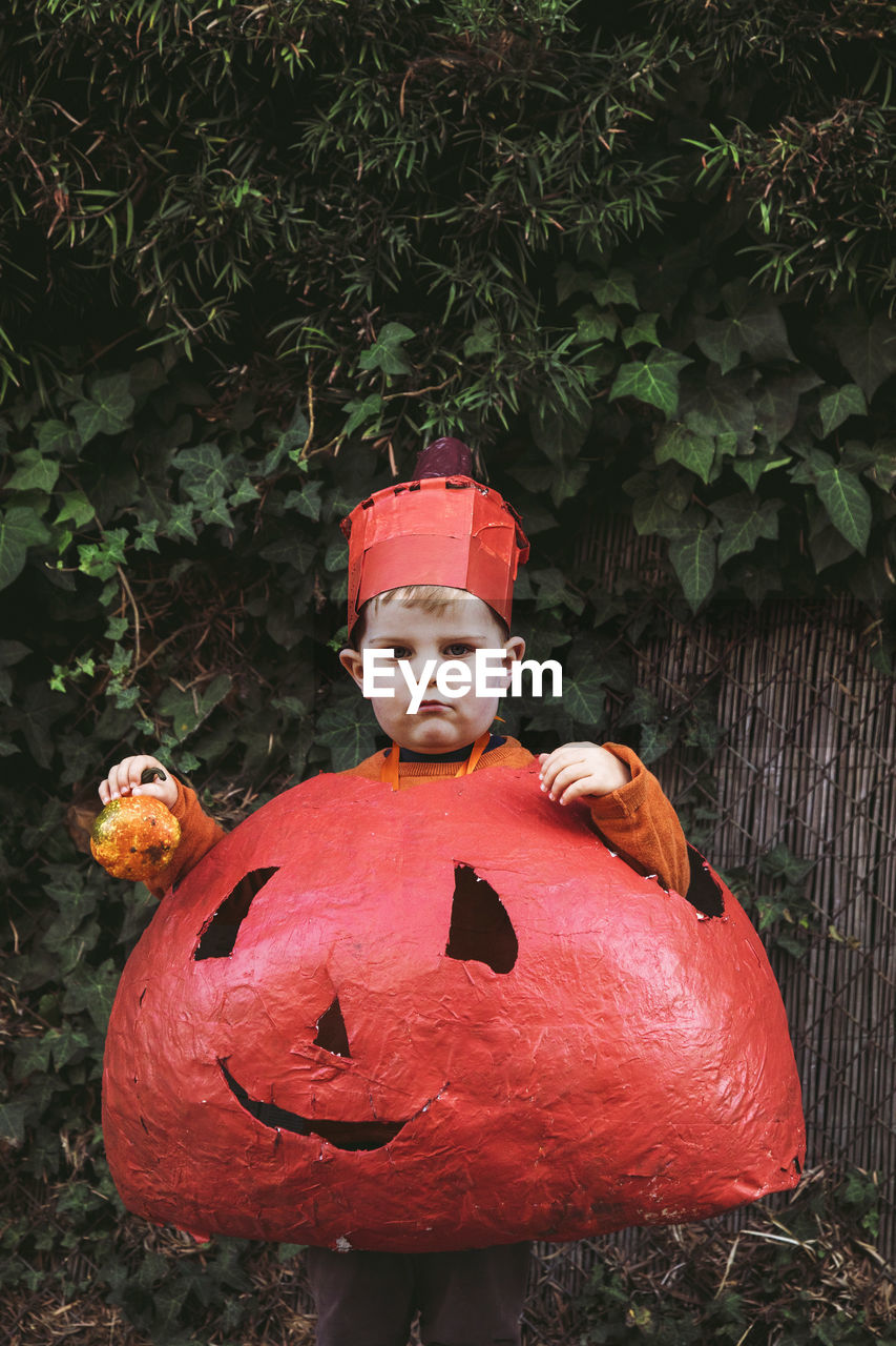 Boy wearing homemade pumpkin halloween costume and holding gourd