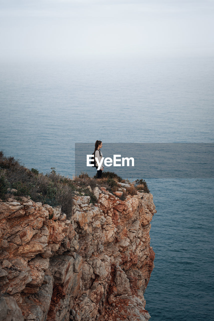 MAN ON ROCK IN SEA