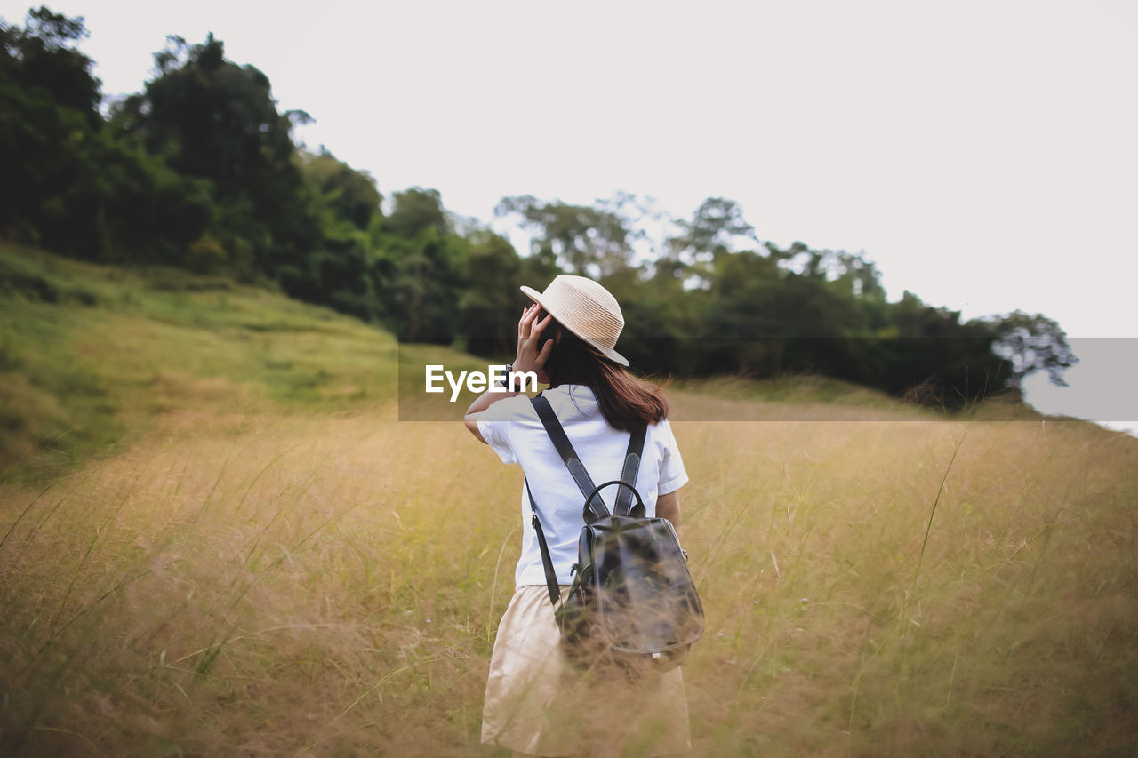 Rear view of woman wearing hat on field against clear sky