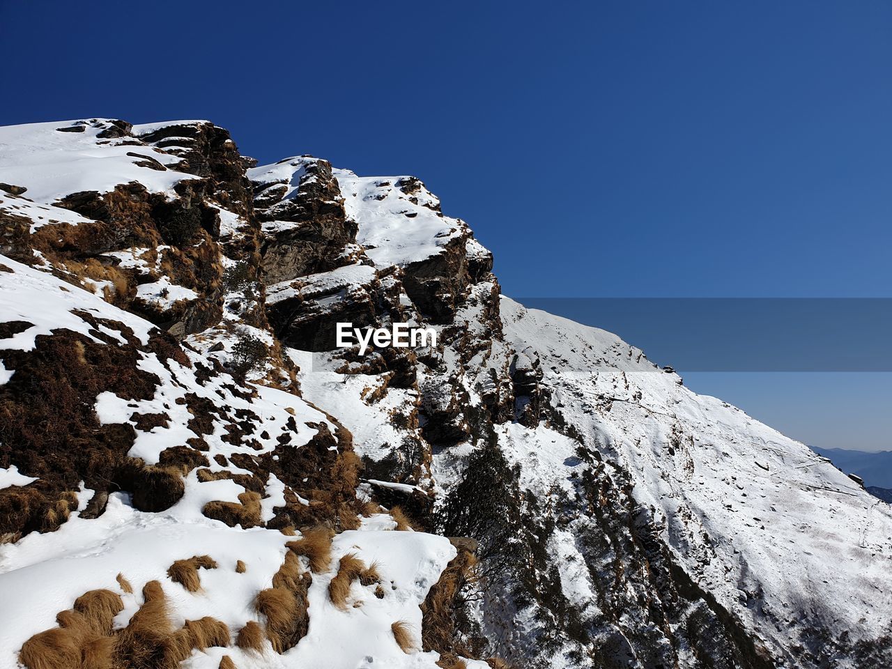 Low angle view of snowcapped mountain against blue sky