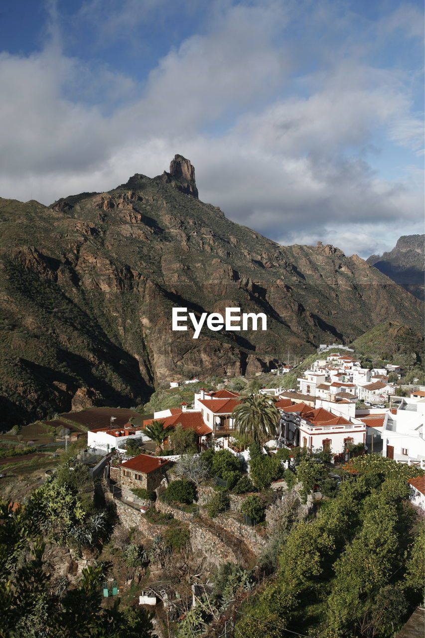 Residential district by mountain against sky