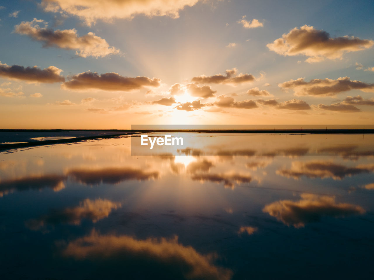 Aerial photo of dramatic sky and clouds at sunset reflected on salt flats in mexico.