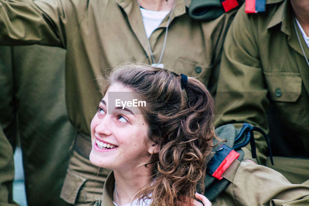 PORTRAIT OF A SMILING YOUNG WOMAN SITTING ON OUTDOORS