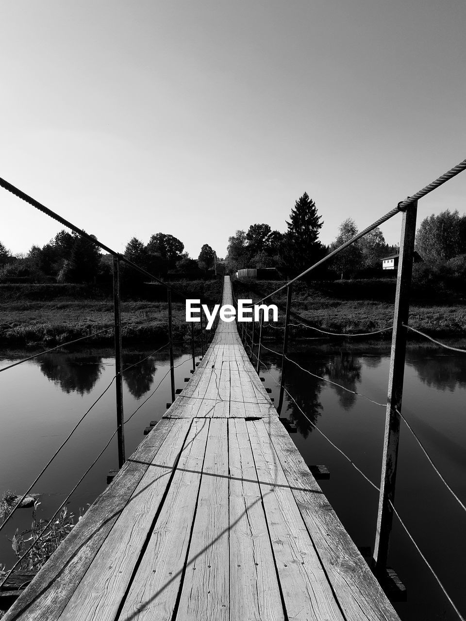 Footbridge over river against clear sky