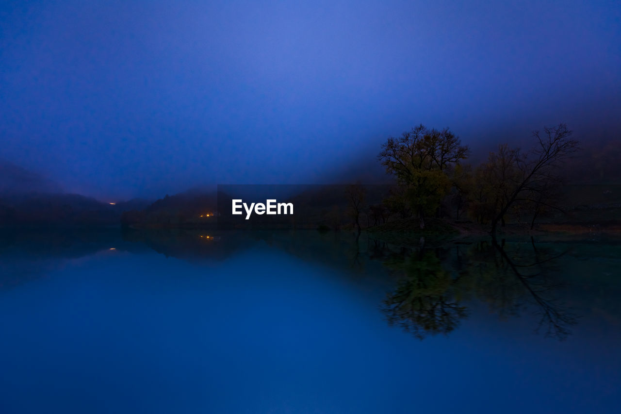 Scenic view of lake against blue sky at dusk