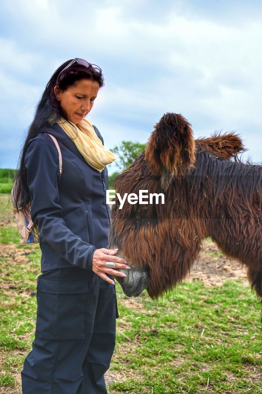 Donkey and woman in grassland.  tenderness moments