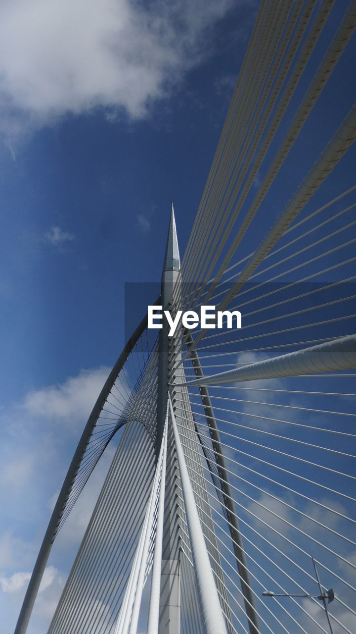 Low angle view of suspension bridge against cloudy sky