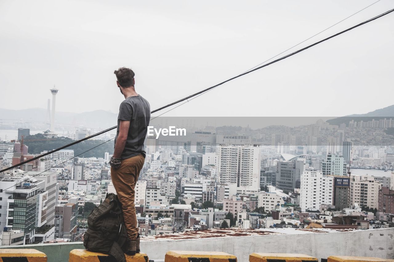 Man standing on seat against cityscape