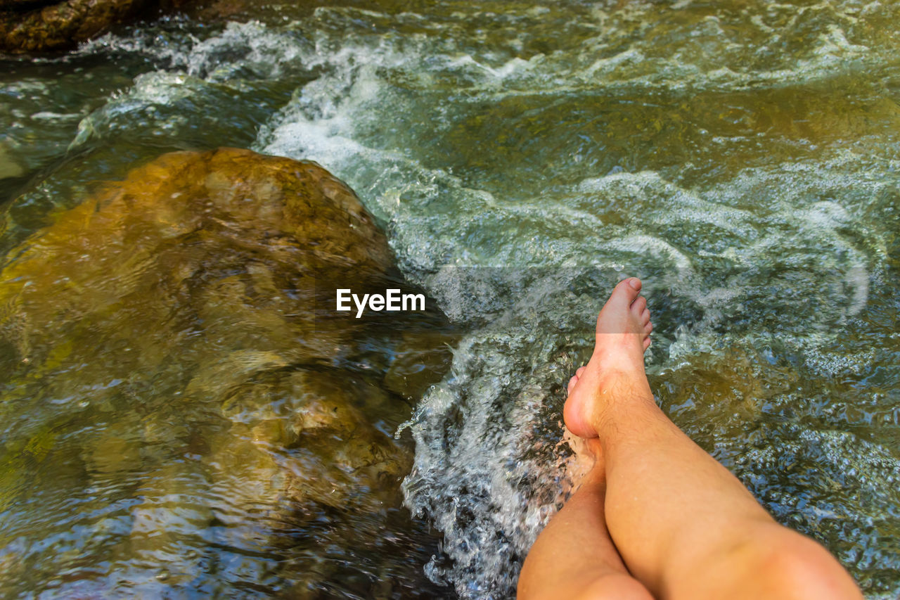Low woman of person legs by flowing water