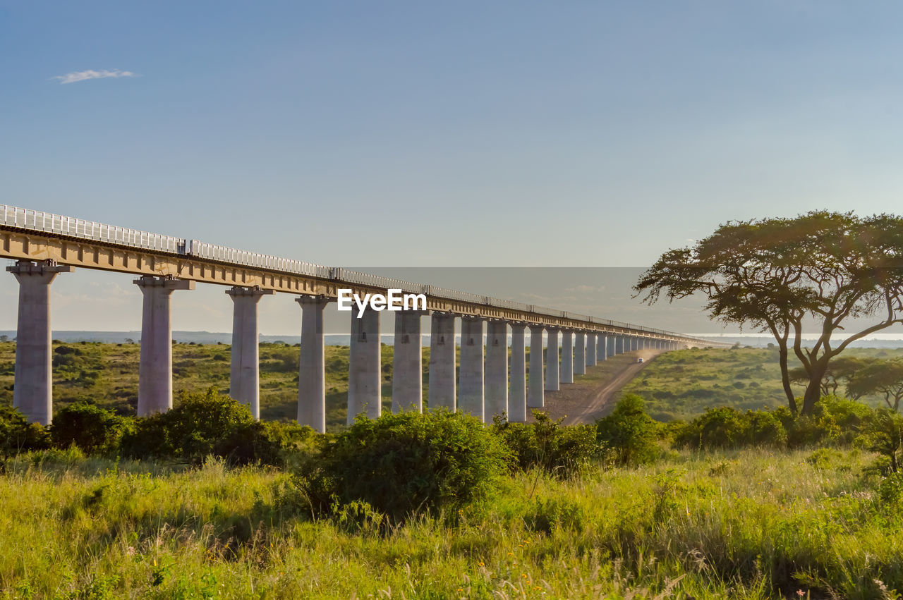 BRIDGE OVER FIELD AGAINST SKY