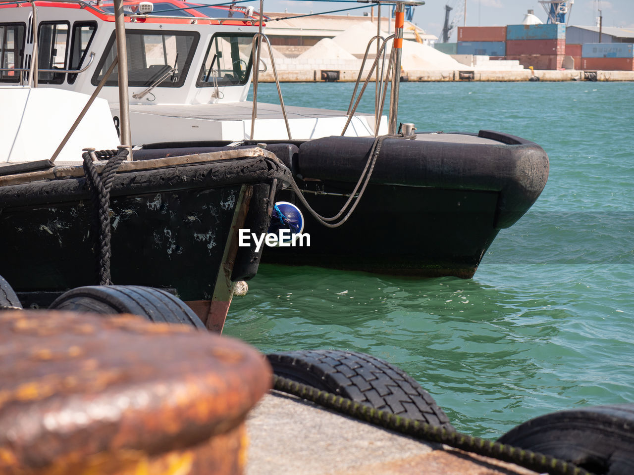 Detail of the bow of two small moored boats used as tugs in port.