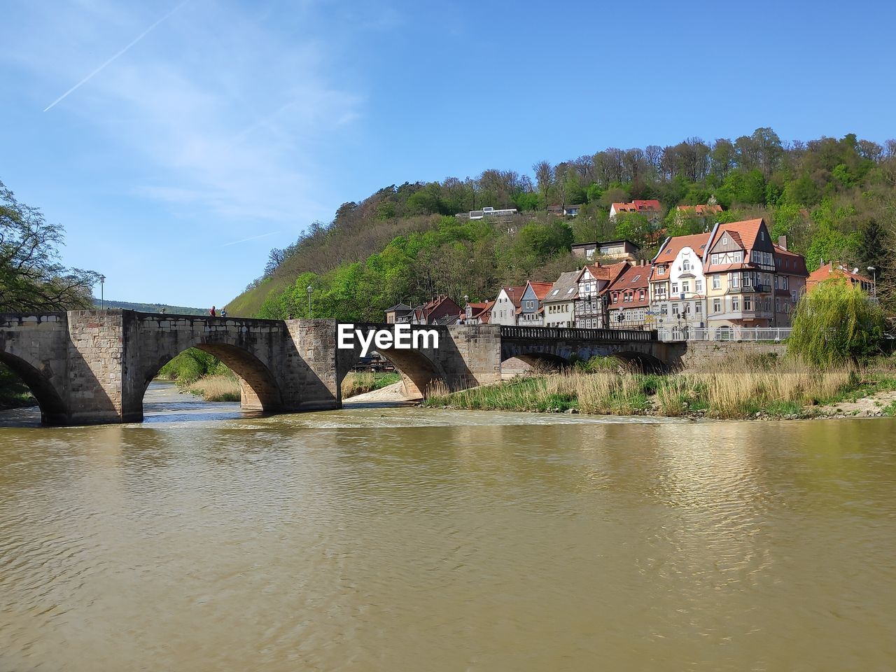 Arch bridge over river by building against sky