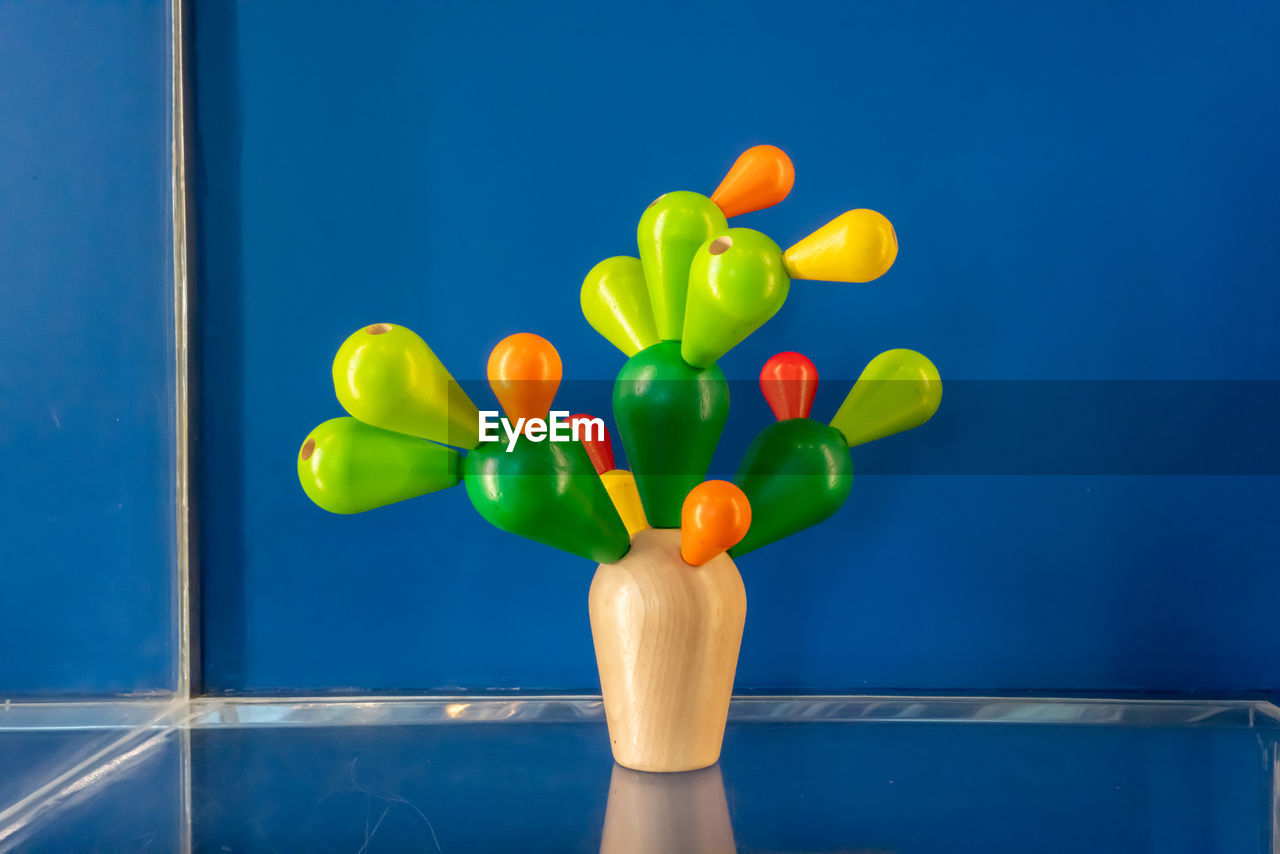 CLOSE-UP OF MULTI COLORED BALLOONS ON BLUE TABLE AGAINST WALL