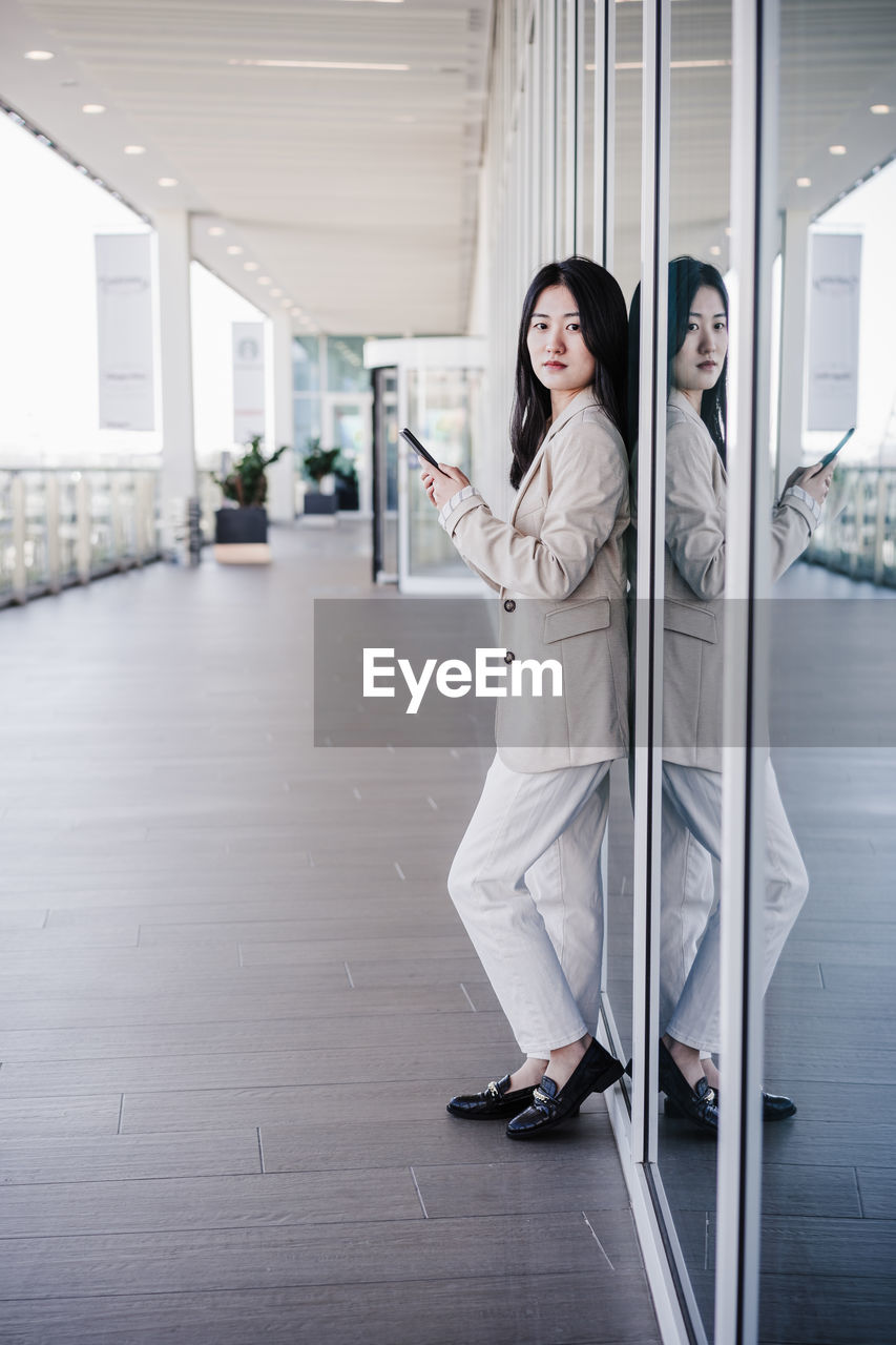 Portrait of beautiful chinese business woman using mobile phone in building office. technology