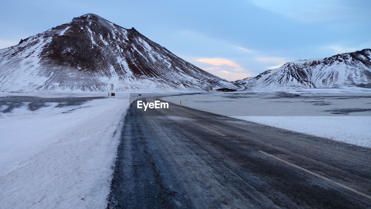 Road amidst snowcapped mountains against sky