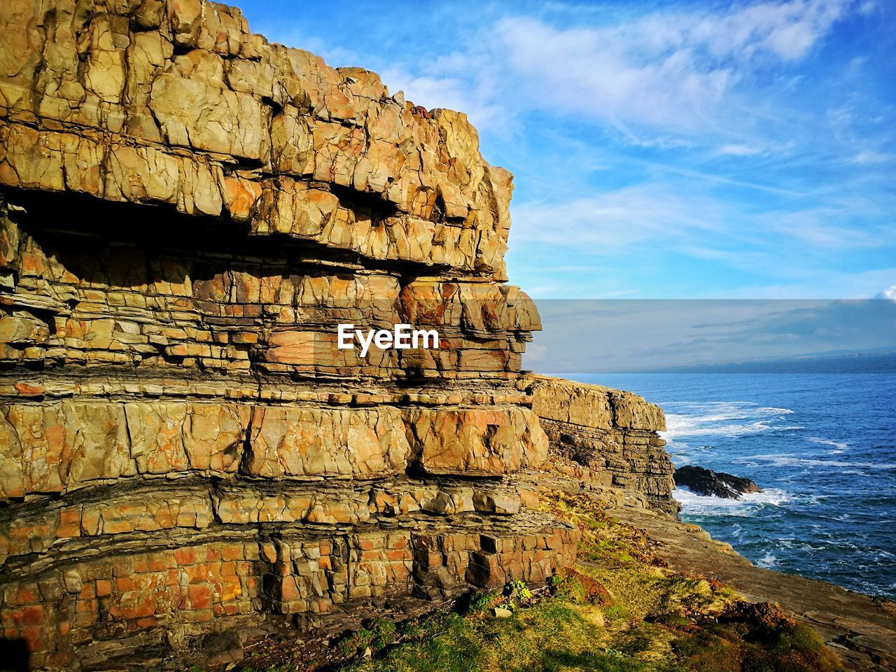 Cliff by sea against sky